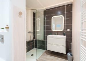 salle de bain lumineuse d’une location saisonnière avec cuisine ouverte et table en bois