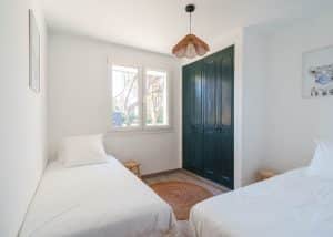 chambre lumineuse d’une location saisonnière avec cuisine ouverte et table en bois