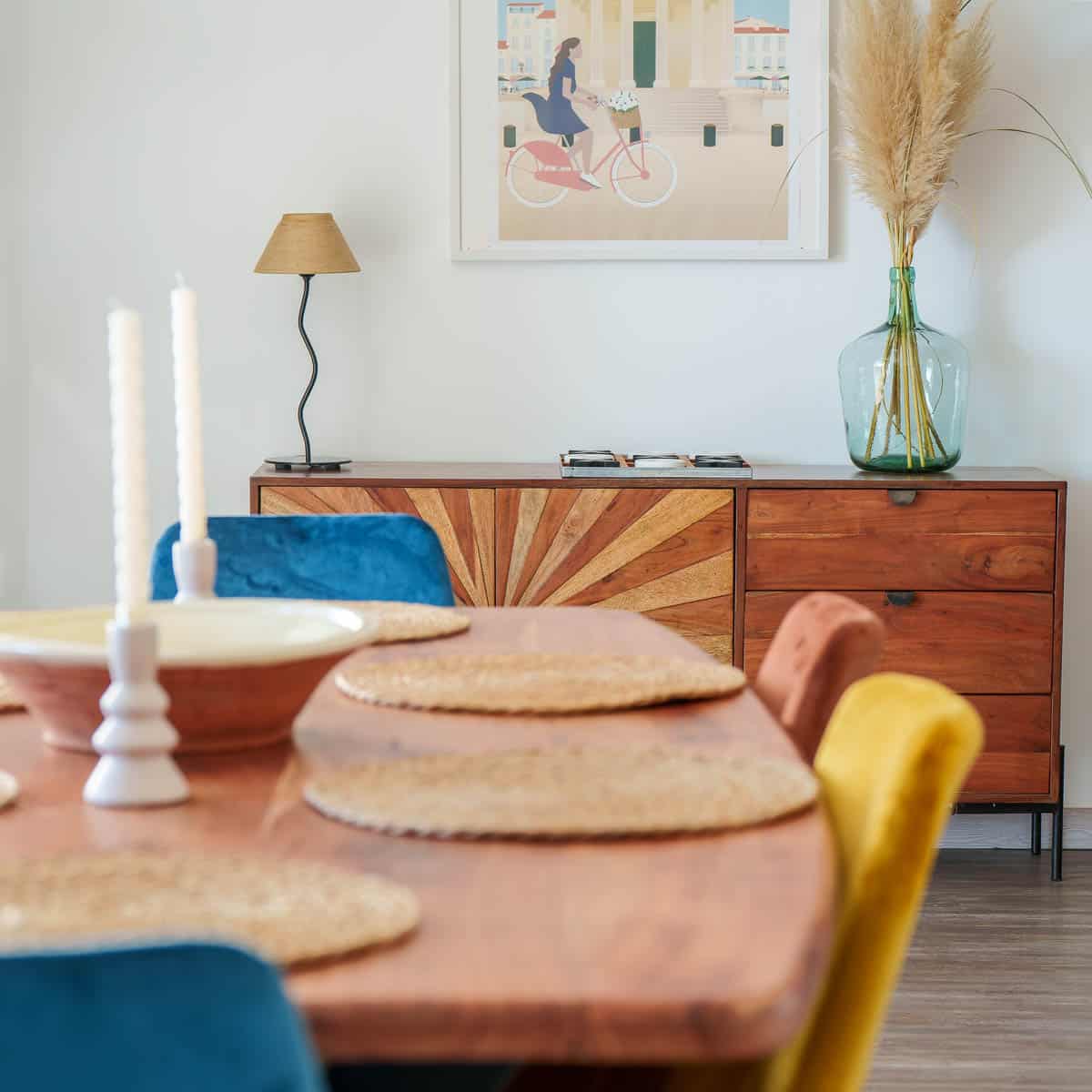 Salon lumineux d’une location saisonnière avec cuisine ouverte et table en bois